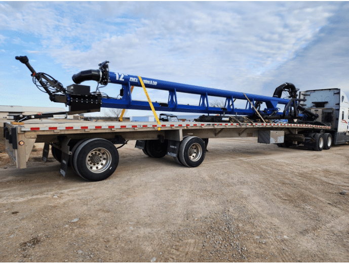 Blue dragline manure equipment loaded on a flatbed trailer for farm use by Phil’s Pumping & Fabrication.
