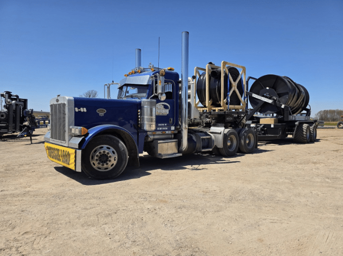 Blue semi-truck transporting large manure hose reels for dragline equipment, supplied by Phil’s Pumping & Fabrication.