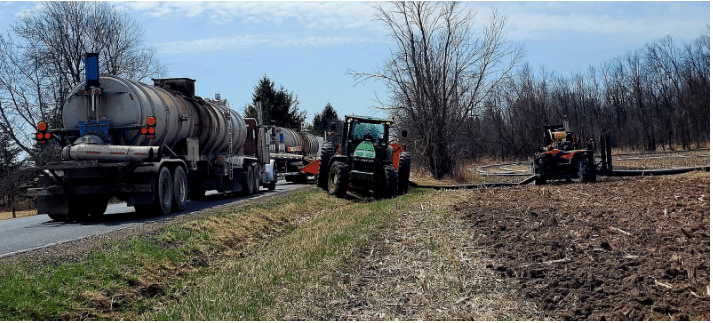 Manure tanker and tractor working together for efficient field application on large-scale farm operations.