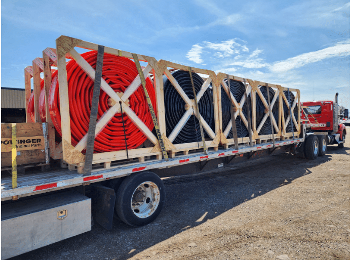 Truck hauling new manure hose reels for upgraded farm nutrient management systems across dairy fields.