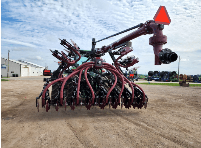 Tractor-mounted manure injection toolbar with hoses for even and controlled nutrient distribution.