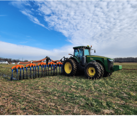 John Deere tractor applying manure with dragline injector toolbar on cover crop field.