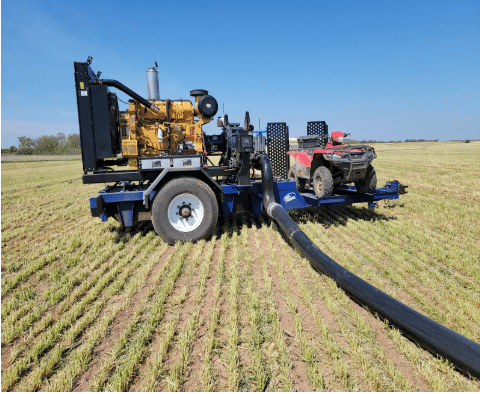 Drag hose manure pumping system setup with pump trailer and ATV in field for efficient liquid manure transfer.