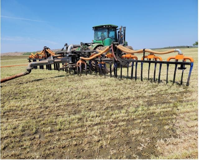 Dragline manure equipment applying slurry through hoses and injectors for uniform nutrient placement in crop field