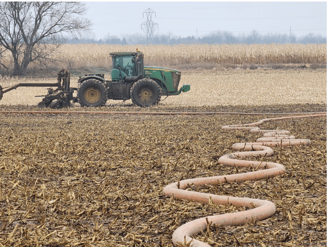 Tractor operating a drag hose manure system in the field for efficient nutrient application with reduced soil compaction.