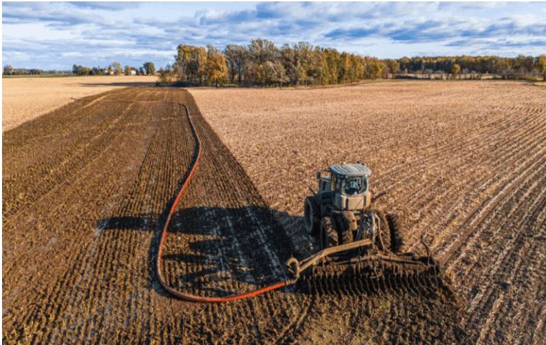Tractor using dragline manure equipment for efficient manure application with minimal field traffic