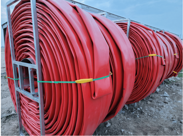 Heavy-duty red drag hose stored on a reel, designed for long-distance manure pumping and durable field performance.
