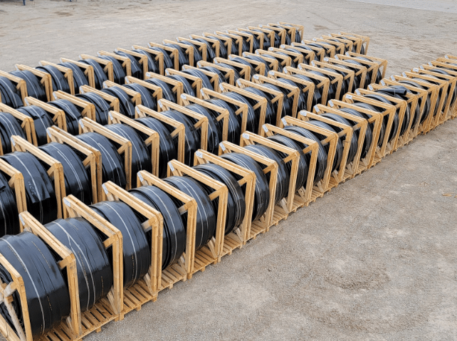 Rows of manure drag hoses stored in wooden crates for protection and long-term field use.